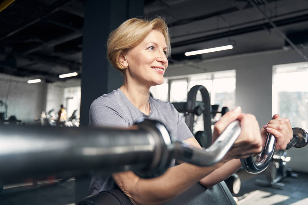 Mujer sonriente haciendo ejercicio con entrenador de gimnasio - Foto, Imagen