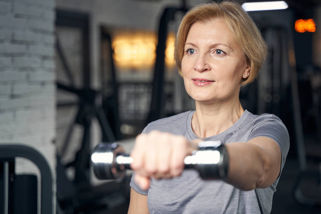 Mujer haciendo ejercicio con la mancuerna en el gimnasio - Foto, Imagen