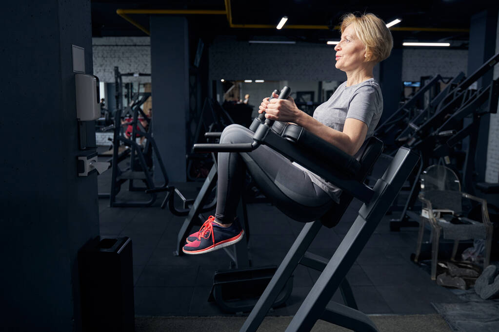 Mujer en ropa deportiva usando equipo de fitness en el gimnasio - Foto, imagen