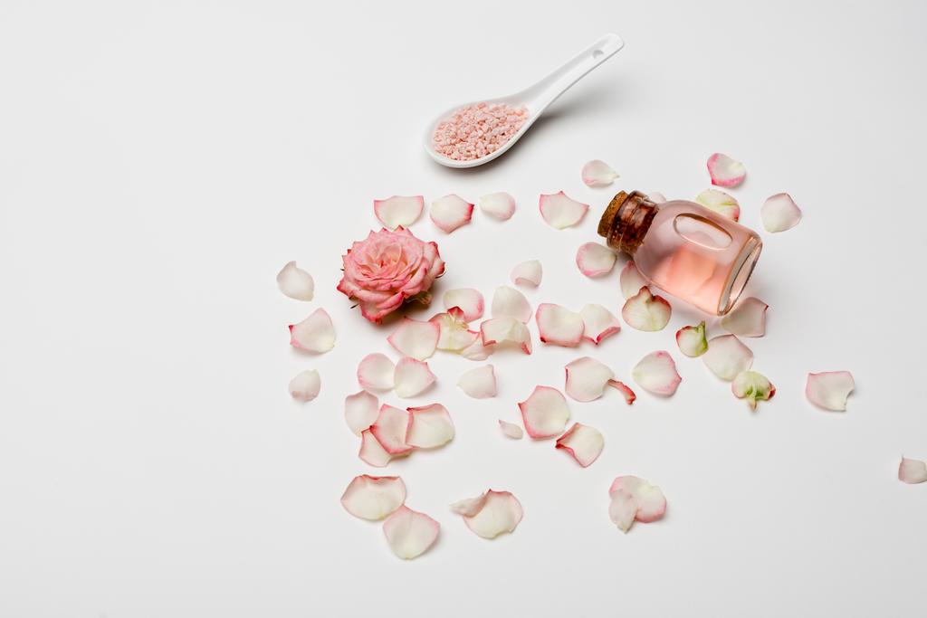 vista ad angolo alto di rosa vicino petali, sale marino rosa e bottiglia con acqua di rosa su bianco - Foto, immagini