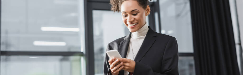 Позитивная африканская американская бизнесвумен с помощью мобильного телефона в офисе, баннер  - Фото, изображение