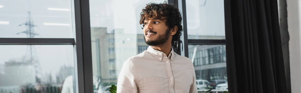 Веселый индийский бизнесмен смотрит в сторону в офисе, баннер  - Фото, изображение