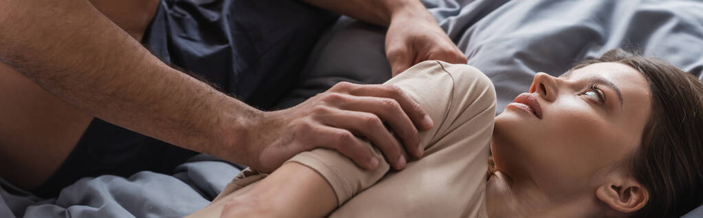 Мужчина без рубашки трогает брюнетку на кровати, плакат  - Фото, изображение