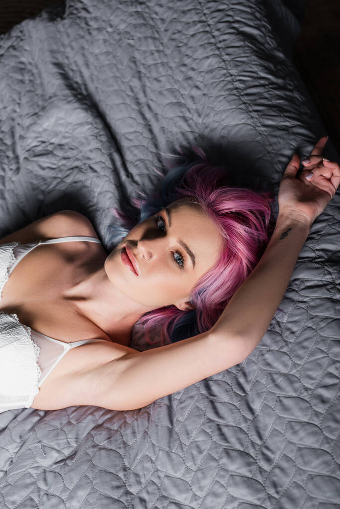 widok z góry tatuaż i sexy młoda kobieta w biały biustonosz leżące na łóżku - Zdjęcie, obraz