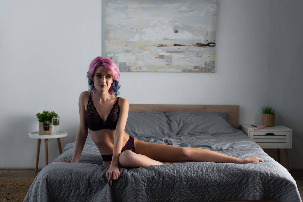 mulher sexy com cabelo tingido em roupa interior de renda escura posando na cama - Foto, Imagem