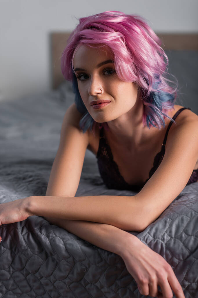 Porträt einer jungen Frau, die in die Kamera blickt und auf dem Bett liegt - Foto, Bild