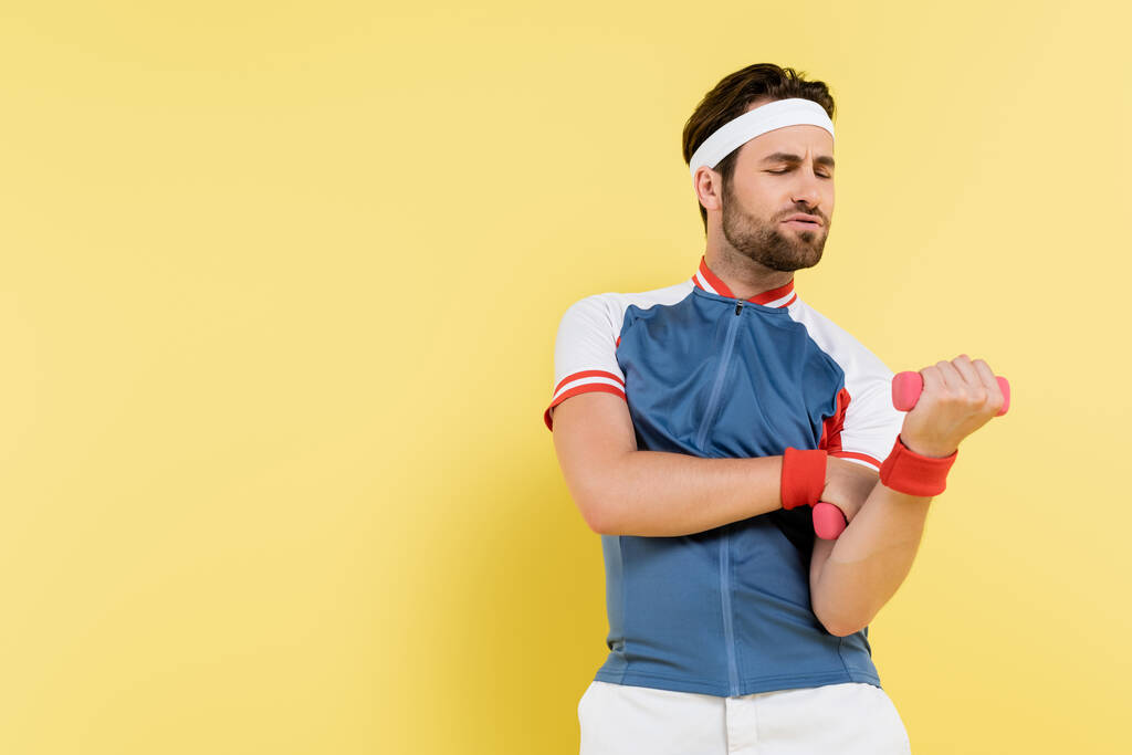 Tensed sportman uit te werken met halters geïsoleerd op geel  - Foto, afbeelding