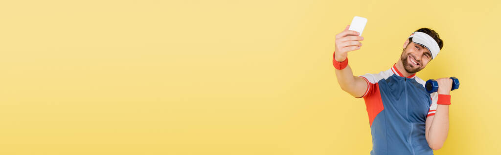 Boldog sportoló selfie és edzés súlyzó elszigetelt sárga, banner  - Fotó, kép