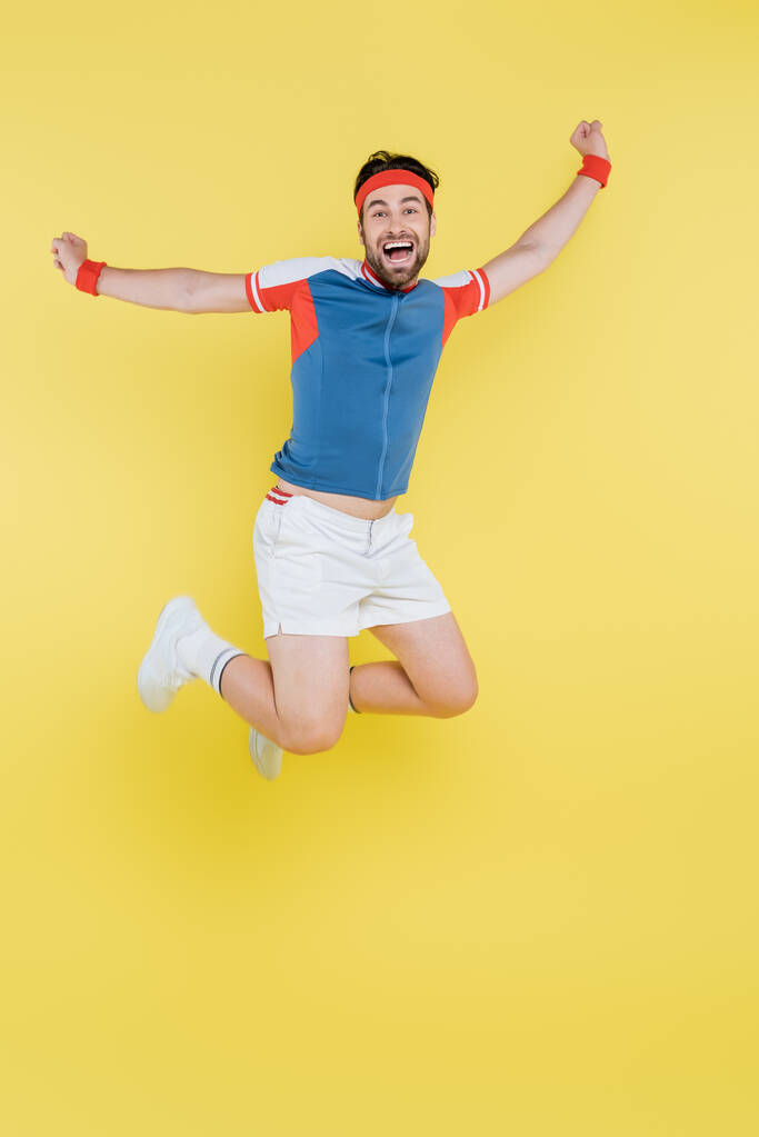 Podekscytowany sportowiec skacze i pokazuje tak gest izolowany na żółto  - Zdjęcie, obraz