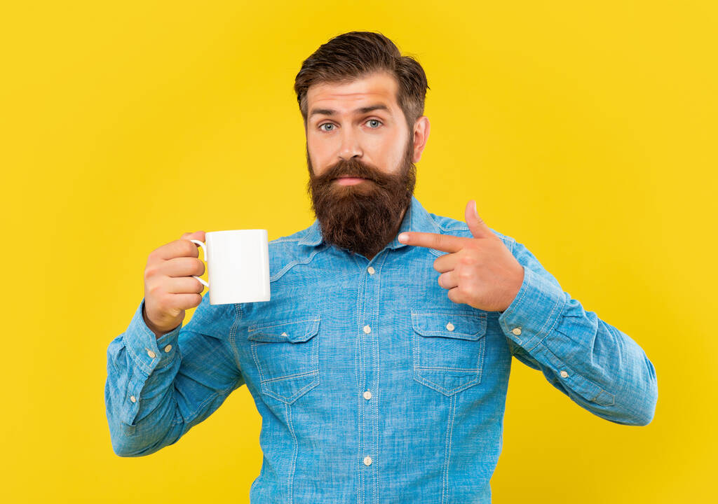 Серйозний чоловік вказує пальцем на кавовий кухоль жовтий фон, копіювати простір
 - Фото, зображення
