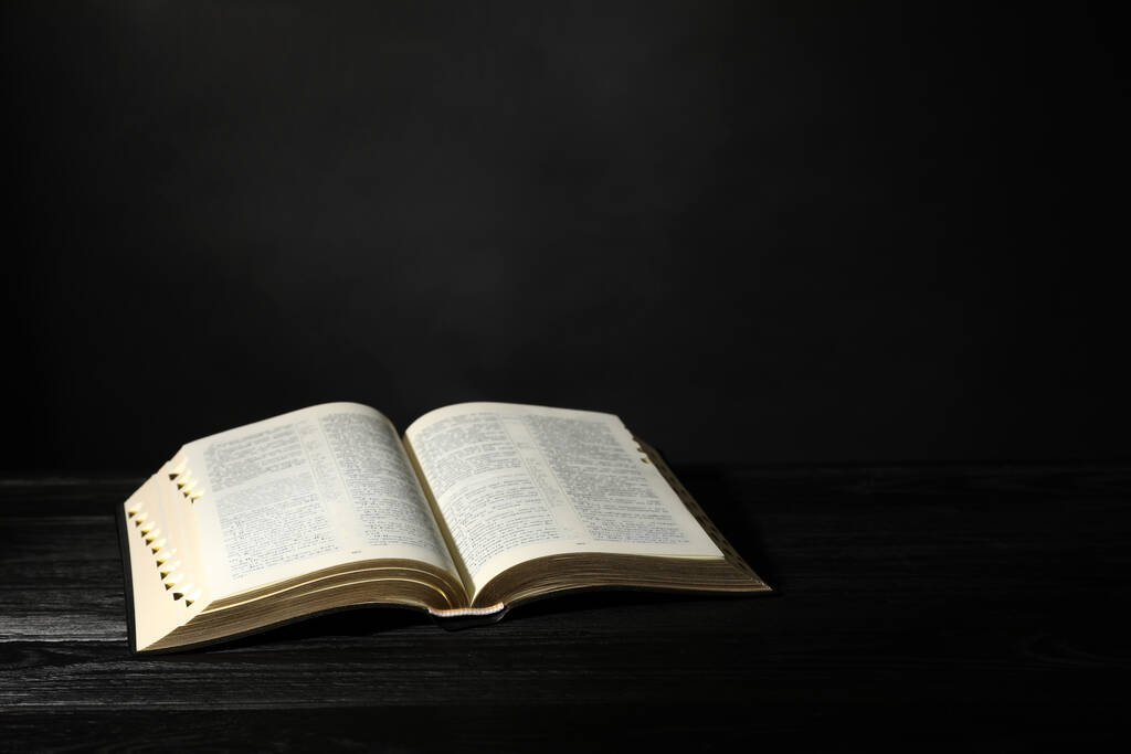 Открытая Библия на черном деревянном столе, место для текста. Христианская книга - Фото, изображение