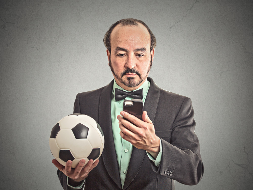 ο άνθρωπος των επιχειρήσεων παρακολουθούν ποδόσφαιρο παιχνίδι στο smartphone - Φωτογραφία, εικόνα