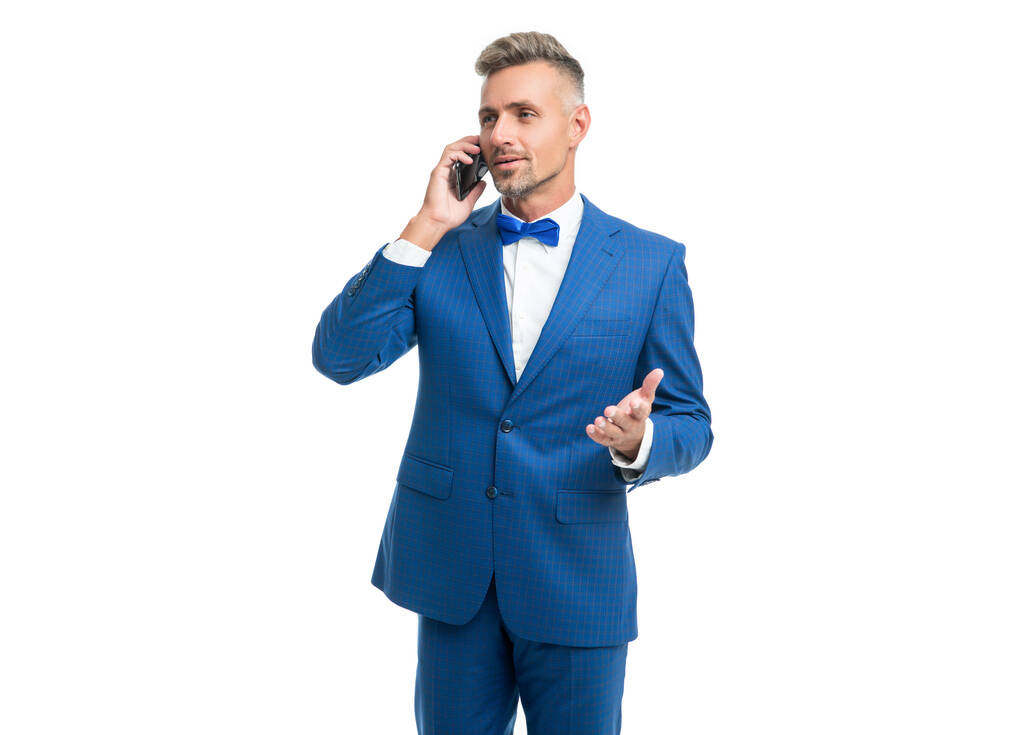 Lächelnder Mann in blauer Fliege im Anzug telefoniert isoliert auf weißem Grund - Foto, Bild