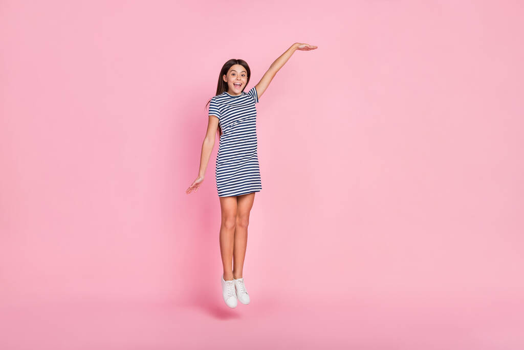 Zdjęcie słodkie ładna dziewczyna ubrana w paski sukienka pokazując ramię puste miejsce skacząc odizolowany różowy kolor tła - Zdjęcie, obraz