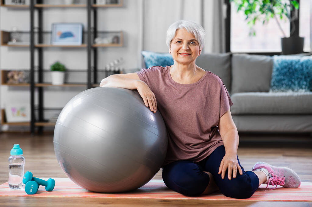 Gülümseyen yaşlı kadın evde egzersiz topuyla - Fotoğraf, Görsel