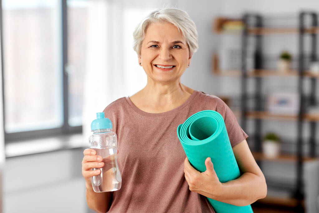старша жінка з йоги килимок і пляшка води
 - Фото, зображення