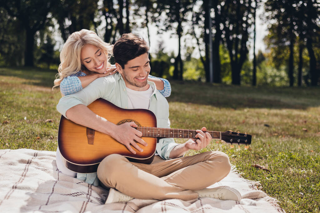 Portrait of two handsome beautiful cheerful couple sitting on plaid singing song pastime on fresh air outdoors - Photo, Image