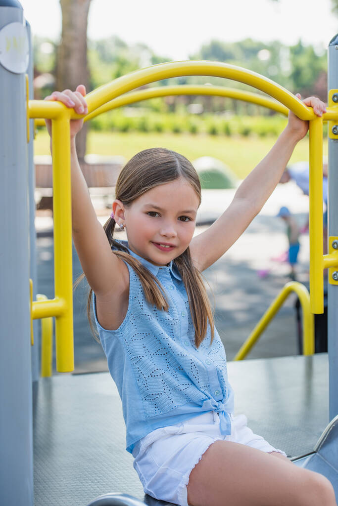 улыбающаяся девушка, смотрящая в камеру, развлекаясь на детской площадке - Фото, изображение