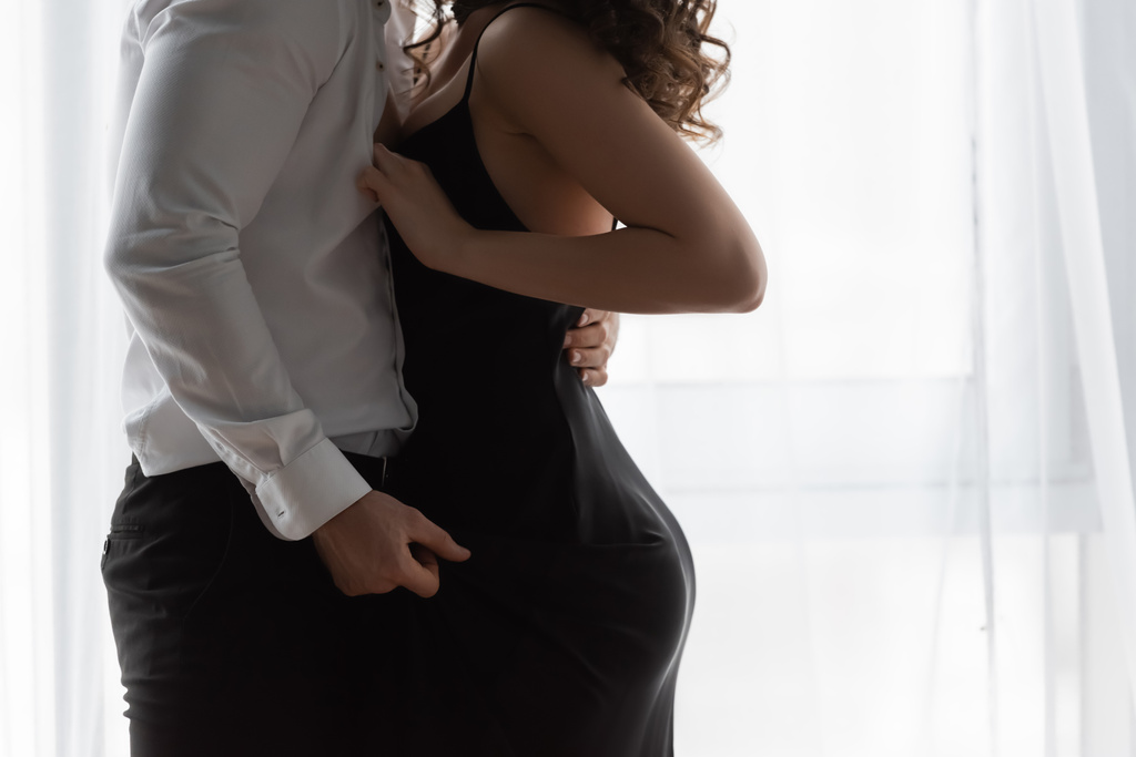 cropped άποψη της παθιασμένης γυναίκας σε ολίσθηση φόρεμα ξεκούμπωμα πουκάμισο του άνδρα - Φωτογραφία, εικόνα