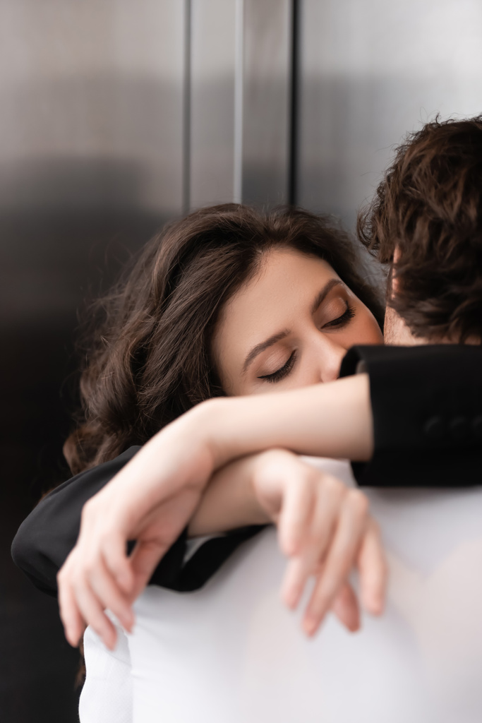 donna riccia con gli occhi chiusi baciare fidanzato vicino ascensore  - Foto, immagini