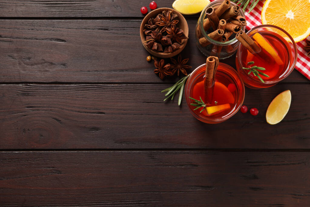 Bebida aromática de ponche e ingredientes en mesa de madera, puesta plana. Espacio para texto - Foto, imagen