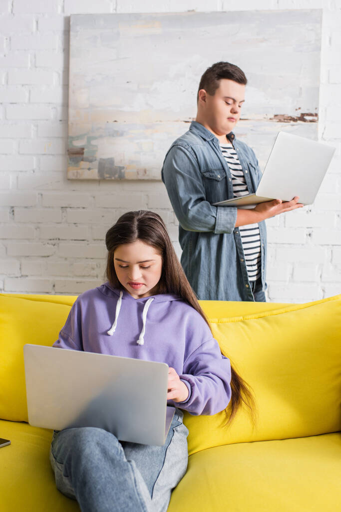 Teen girl with down syndrome using laptop near friend at home  - Photo, Image