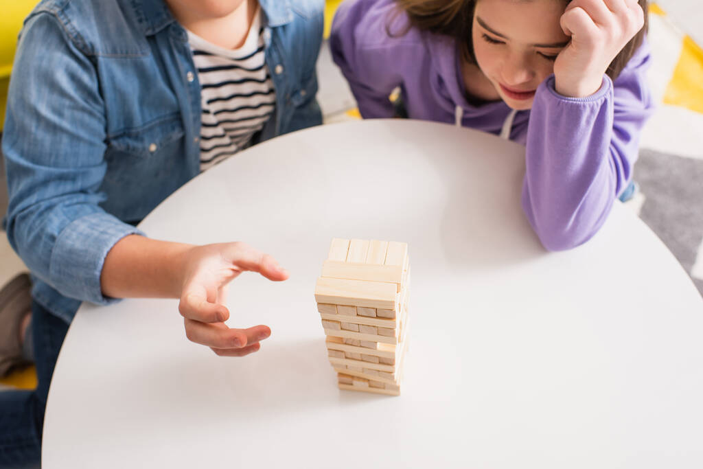 Visão superior do adolescente jogando jogo de blocos de madeira perto de amigo com síndrome de down em casa - Foto, Imagem