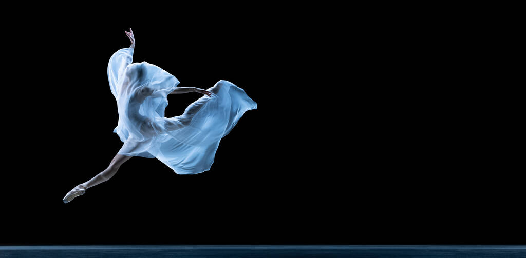 Bailarina clásica elegante bailando con tela ingrávida aislada sobre fondo de estudio negro en neón. Volante - Foto, imagen