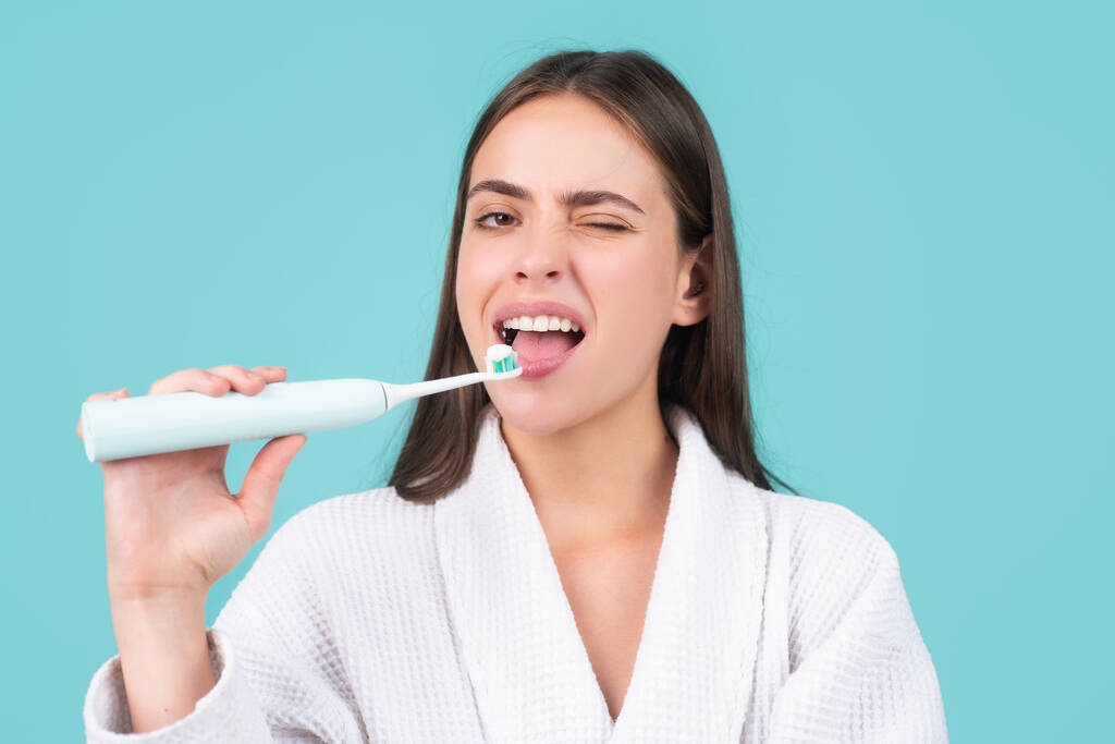 Mooie jonge vrouw met gezonde tanden, mooie vrouwelijke glimlach. Elektrische tandenborstel. Close-up van jonge vrouw houdt een tandenborstel vast. - Foto, afbeelding