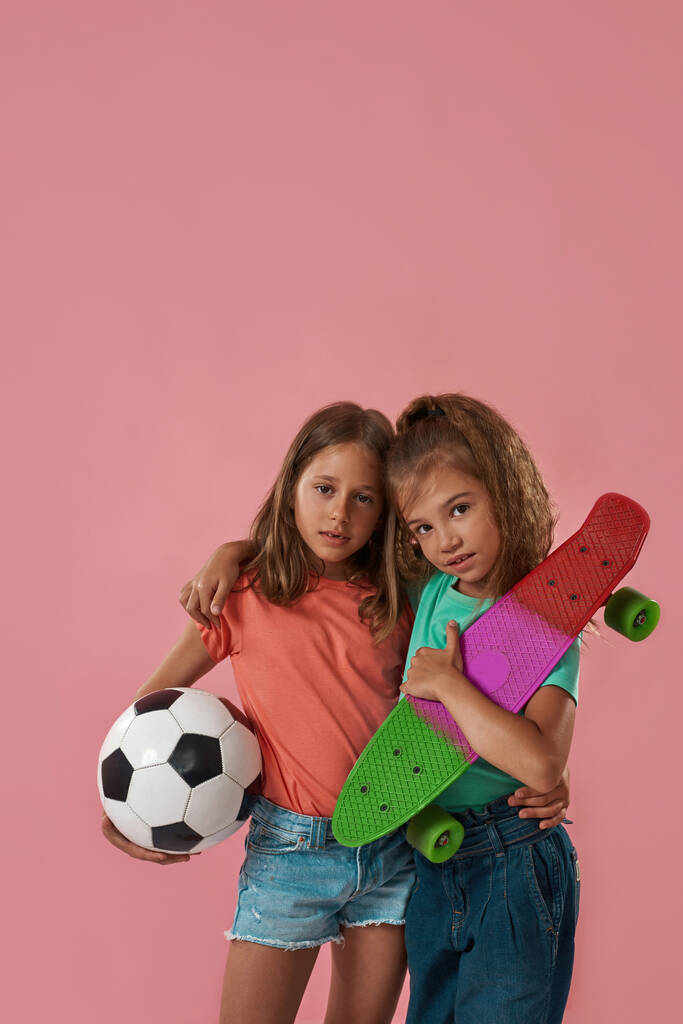 Bambine tenere palla e skateboard e abbraccio - Foto, immagini