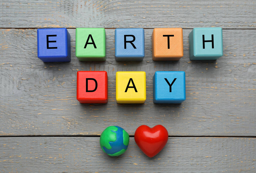 Cubes colorés avec des mots Jour de la Terre, planète plasticine et coeur décoratif sur table en bois gris, pose plate - Photo, image