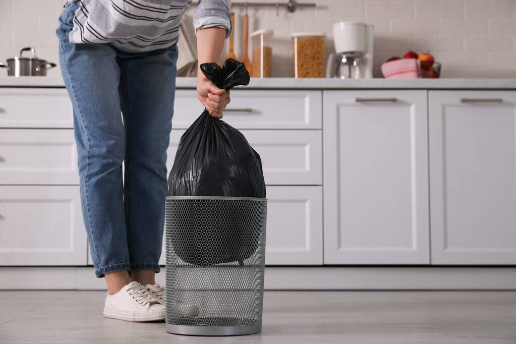 Mujer sacando la bolsa de basura de la papelera en casa, primer plano - Foto, imagen