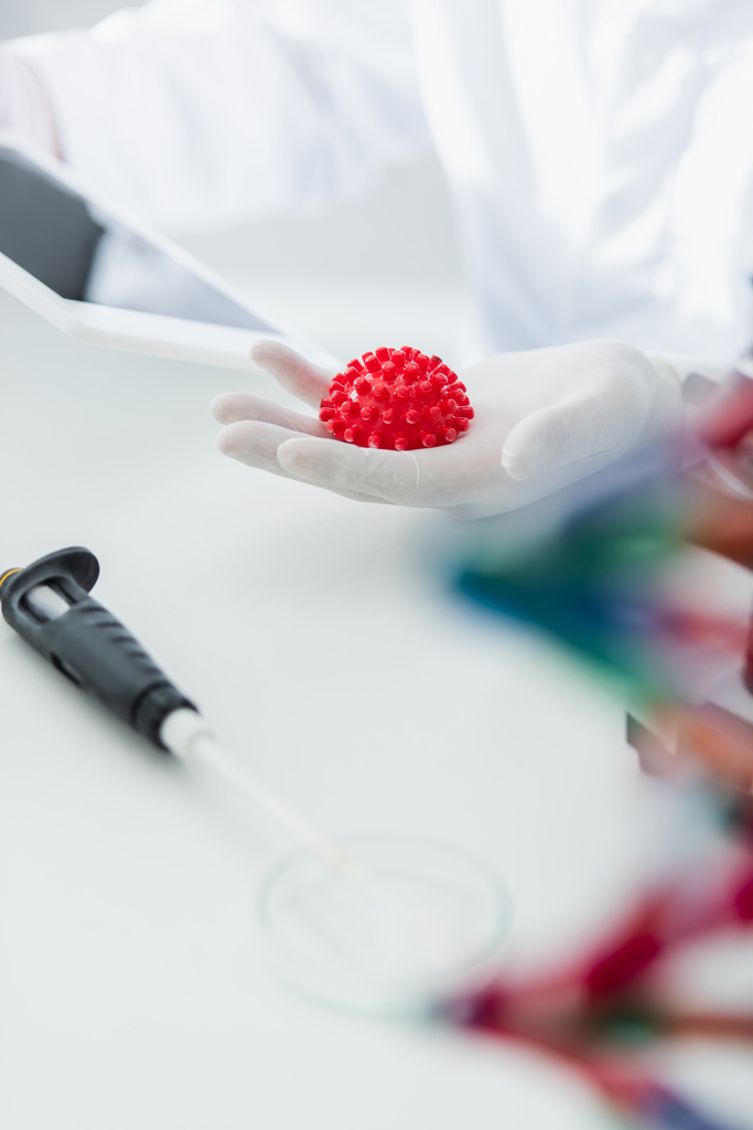 červený koronavirus bakterie model v ruce oříznutý virologa na rozmazaném pozadí - Fotografie, Obrázek