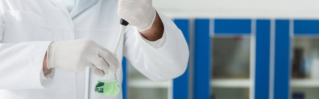 partial view of biologist holding micropipette and flask with liquid, banner - Photo, Image
