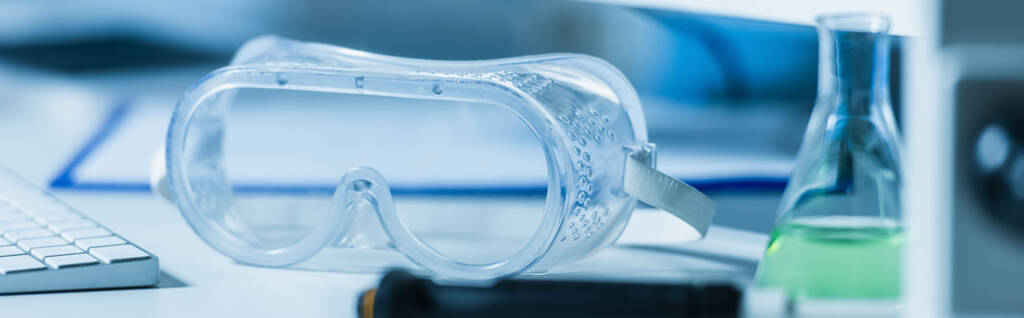 doorzichtige brillen in de buurt van wazig kolf in laboratorium, spandoek - Foto, afbeelding