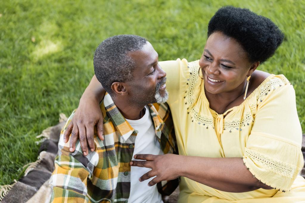 vue grand angle de couple afro-américain senior étreignant et souriant dans le parc - Photo, image
