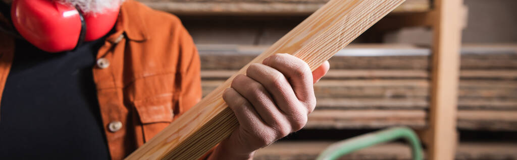 partial view of furniture designer holding plank in carpentry workshop, banner - Photo, Image