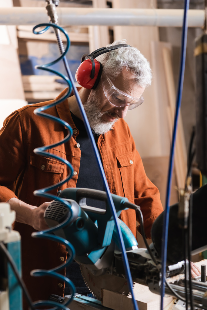 barbuto falegname di mezza età che lavora con mitra sega in officina - Foto, immagini