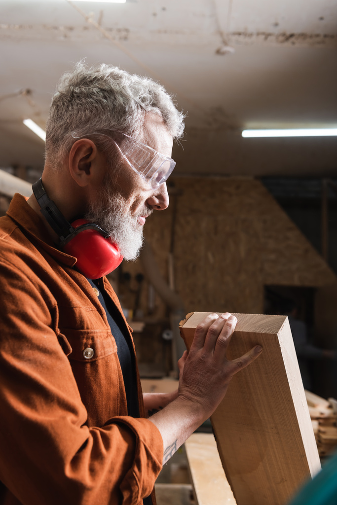 designer de meubles positif dans les lunettes de contrôle de la planche en bois dans l'atelier - Photo, image