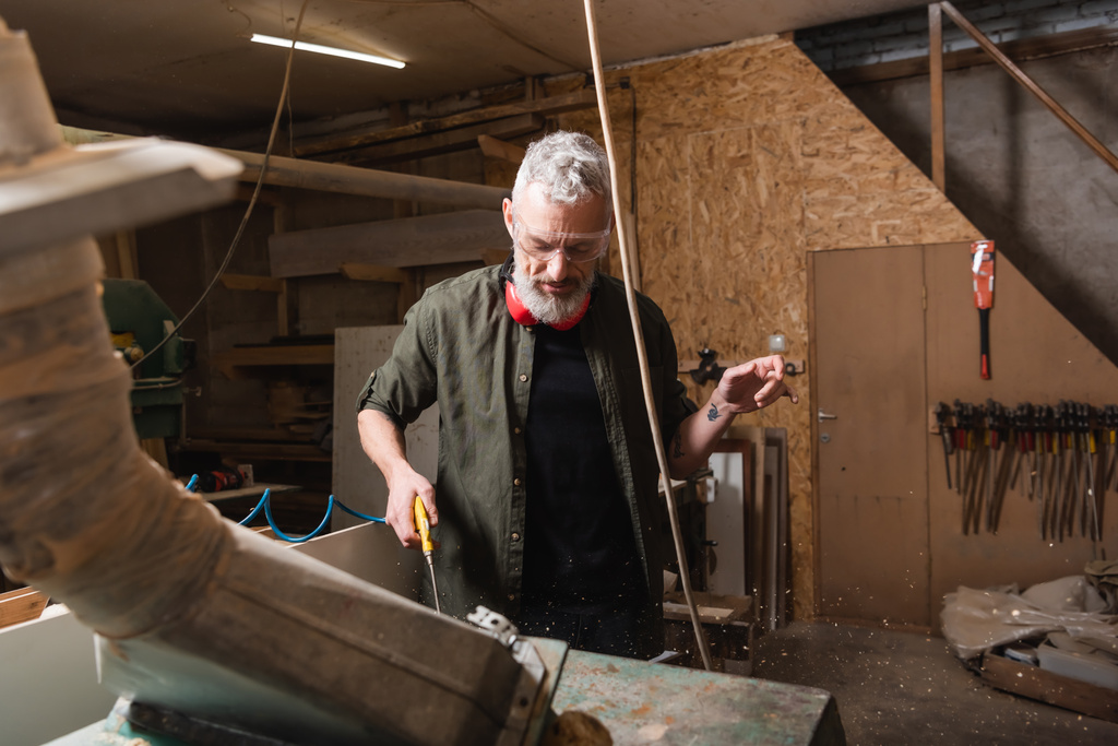 mature grey haired carpenter in goggles working near ventilation hood - Photo, Image