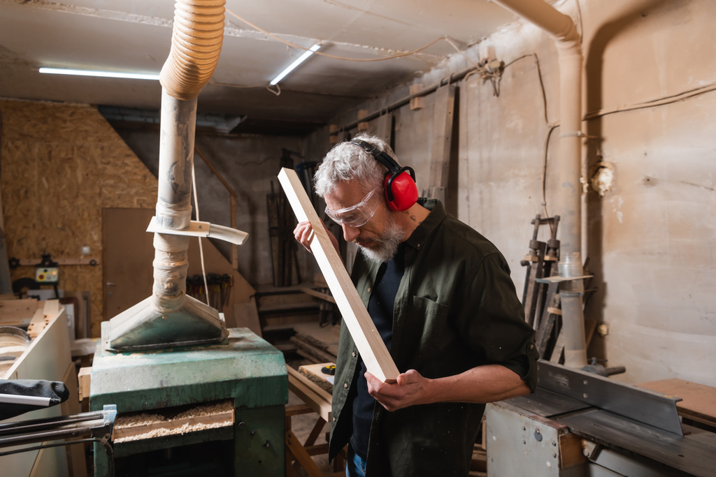 працівник деревини в окулярах і захисні вуха контрольної дошки в майстерні
 - Фото, зображення