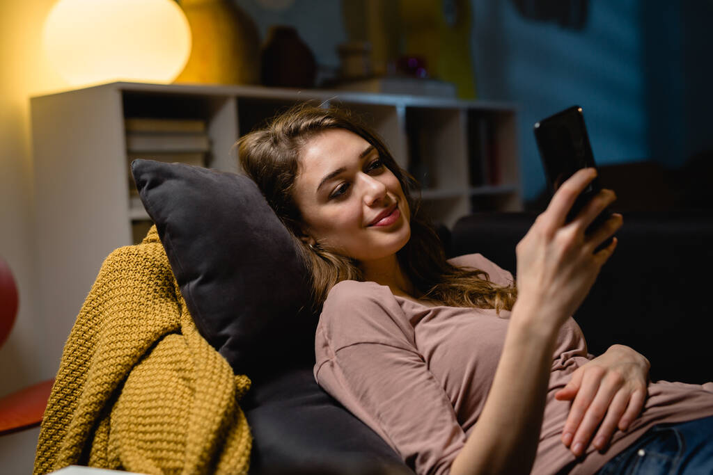giovane donna che si rilassa a casa utilizzando smartphone - Foto, immagini