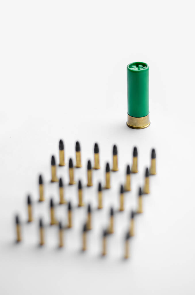 vista de ángulo alto de balas borrosas cerca de la escopeta sobre fondo blanco  - Foto, imagen
