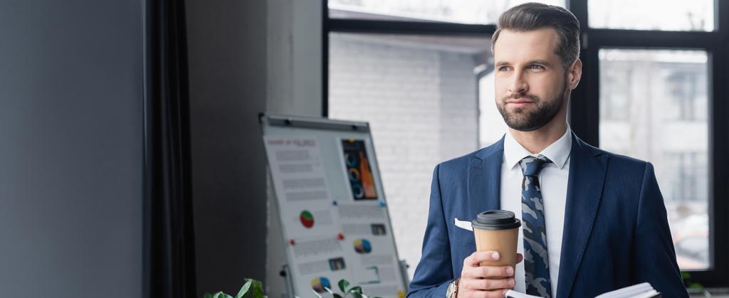 economist with coffee to go looking away near blurred flip chart in office, banner - Photo, Image
