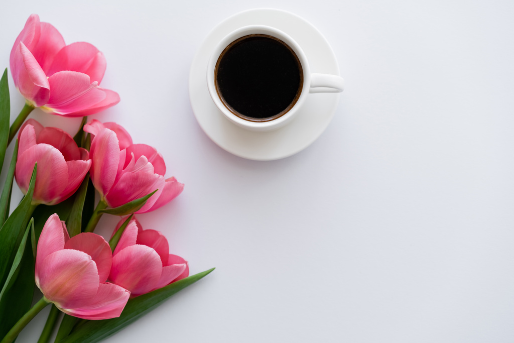 bovenaanzicht van boeket tulpen in de buurt van kopje koffie op wit  - Foto, afbeelding