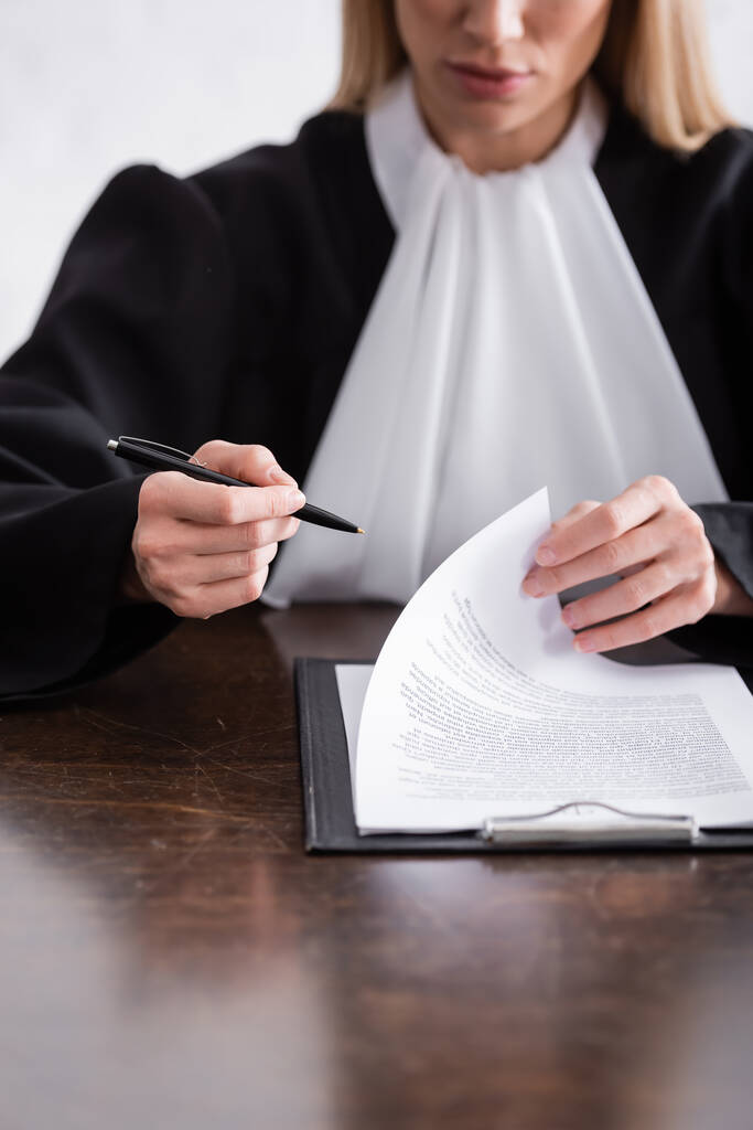 Bulanık yargıcın elinde kalem tutarken kısmi görüntüsü - Fotoğraf, Görsel