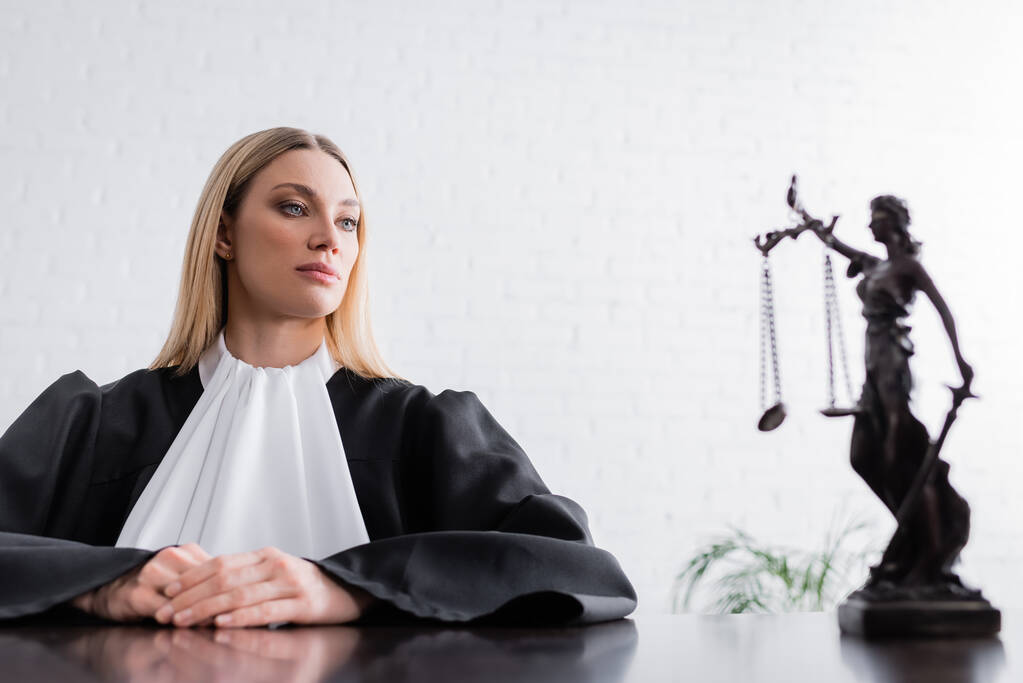 blondýny žalobce v plášti při pohledu na ně socha na rozmazané popředí - Fotografie, Obrázek