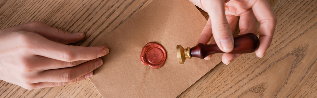 częściowy widok stempla notarialnego w pobliżu koperty z uszczelką woskową na drewnianym biurku, baner - Zdjęcie, obraz