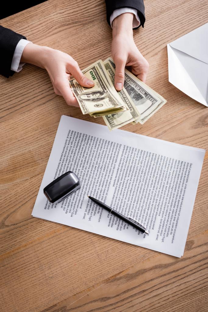 top view vágott ügyvéd számlálás pénzt közel szerződés és bélyegző fa íróasztal - Fotó, kép