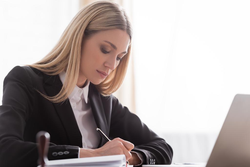 blonde notary in formal wear writing in office - Photo, image